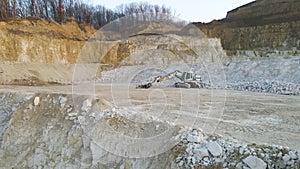 Open pit mining site of construction sand stone materials with excavator equipment for digging of gravel resources at