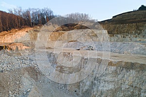 Open pit mining site of construction sand stone materials with excavator equipment for digging of gravel resources at