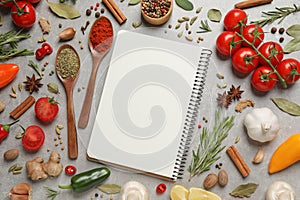 Open recipe book and different ingredients on grey table, flat lay. Space for text