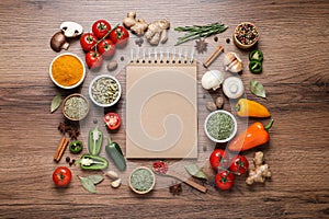 Open recipe book and different ingredients on wooden table, flat lay. Space for text