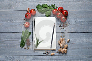 Open recipe book and fresh products on wooden table, flat lay. Space for text