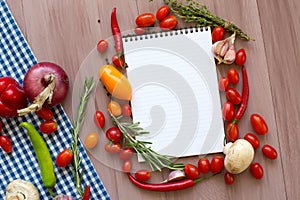 Open recipe book with fresh vegetables and herbs on wooden.