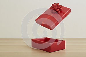 Open red gift box with red ribbon on wooden