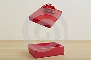 Open red gift box with red ribbon on wooden