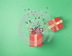 Open red gift box with various party confetti