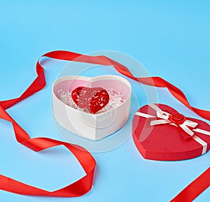 Open red heart-shaped gift box with a bow on a blue background