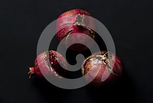 open red ripe pomegranates ready to eat on a black background overhead view photo