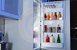 Open refrigerator full of products in stylish kitchen