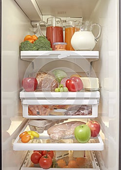 An open refrigerator with healthy fruits, vegetables, meat