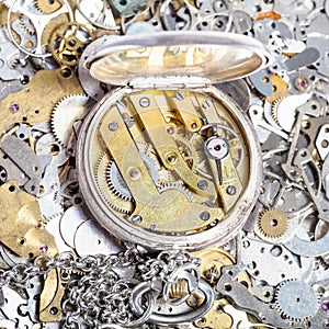 Open retro pocket watch on heap of spare parts