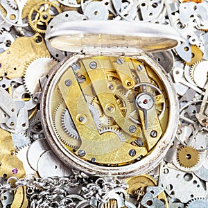 Open retro pocket watch on pile of spare parts