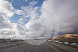 Asphalt road and bright blue sky with fluffy clouds . Empty desert asphalt road from low angle with mountains and clouds on