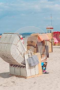 Open roofed chairs with tourist on sandy beach in Travemunde, Germany