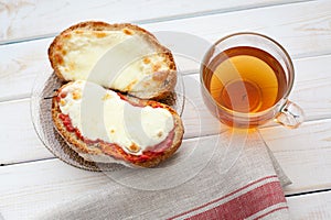 Open sandwich with cheese and cup of tea on wooden table. Breakfast concept