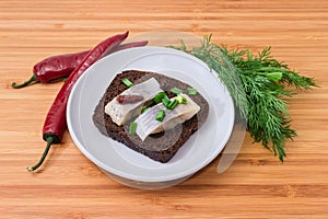 Open sandwich with pickled herring slices on brown bread, chili