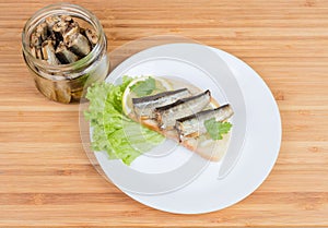 Open sandwich with preserved smoked sprats and jar with sprats