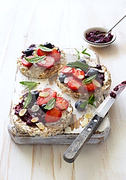 Open sandwiches with cream cheese, strawberries, blueberries, jam and almond flakes close up