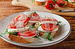 Open sandwiches with fresh mozzarella, tomatoes and arugula. Italian food