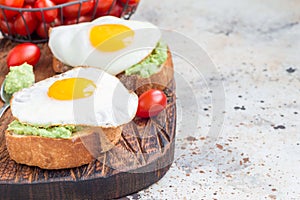 Open sandwiches with mashed avocado and fried egg on a toasted bread, horizontal, copy space