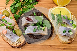 Open sandwiches with pickled herring on cutting board close-up