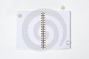 Open school notebook on spring with clean lined sheets and gold metal clips on white desk. Back to school concept