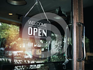 Open sign board with white text on black vintage wooden sign `Welcome we are open please come in`.