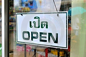 Open sign broad through the glass of window in rainy day with man holding umbrella reflected mirror.