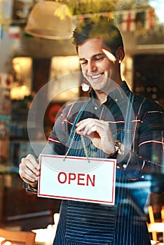 Open sign, smile and man with business, startup success and service with restaurant, window and coffee shop. Male person