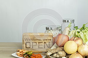 An open sign on table with fruits and vegetables and kimchi. Open sign near organic food ingredients