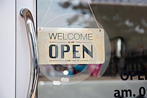 Open sign wooden broad through the glass of window at coffee shop