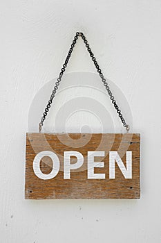 Open sign on wooden planks hanging on the white wall.