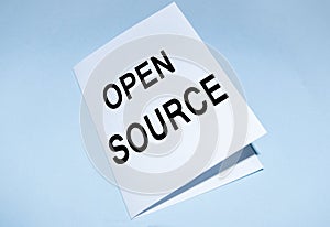 Open source text on a white sheet  on a blue background. A concept photo showing the software whose source code is freely