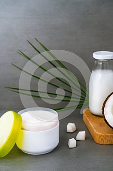 Open spa cream for body skincare and hair with coconut oil, fresh coconuts, palm leaf and bottle with coconut butter on