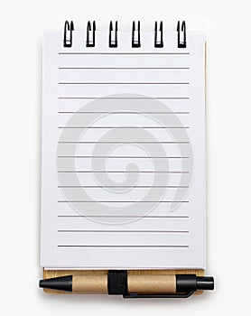 Open spiral lined paper notebook with small pen on white background