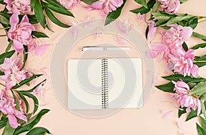 open spiral notebook with blank pages and a white pen on a peach background