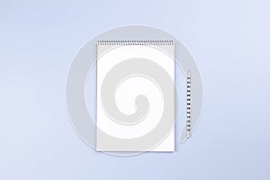 Open spiral notebook with blank white page and pencil on light gray desk background. Top view, copy space for text