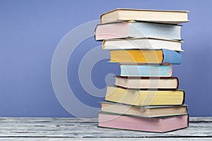 Open stacking book, hardback colorful books on wooden table and blue background. Back to school. Copy space for text. Education