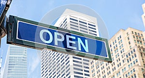 Open street sign, blue color. Highrise buildings and blue sky background