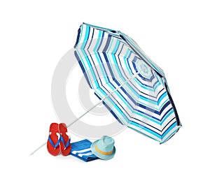Open striped beach umbrella, towel, flip flops and hat on white background