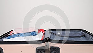 Open suitcase with folded clothes and blank background space
