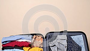 Open suitcase with folded clothes and blank background space
