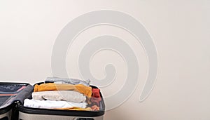 Open suitcase with folded clothes and blank background space