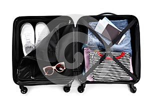 Open suitcase packed for travelling on white background