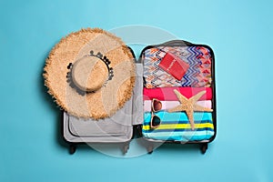 Open suitcase with traveler`s belongings on color background