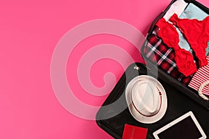 Open suitcase with traveler`s belongings on color background. Space for text