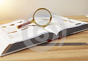 Open technical book for study physics with magnifying glass and ruler