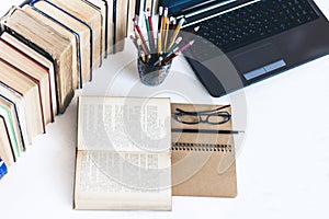 Open textbook, notebook, laptop computer, stack of books education back to school background, glasses and pencils in holder with