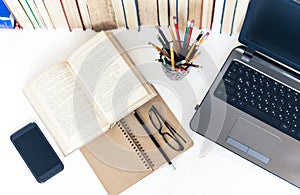 Open textbook, notebook, smartphone, laptop computer, stack of books education back to school background, glasses and pencils in