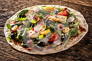 Open top vegetarian tortilla with salad, raddish, chery tomatoes, olives, pomegranate and grilled haloumi cheese photo