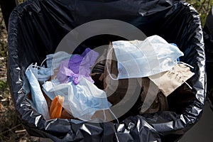 Open trash can with waste resulting from the pandemic of coronavirus Covid-19. Nitrile or latex gloves and medical masks as a new